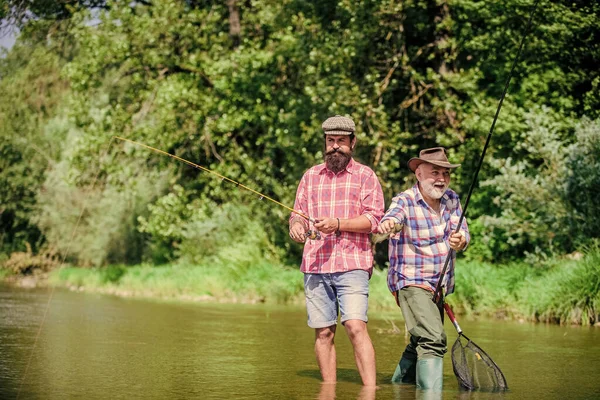 having fun. Fly Fishing Time. hobby. two happy fisherman with fishing rod and net. Camping on the shore of lake. hunting tourism. father and son fishing. Big game fishing. friendship.