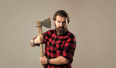 Gerçek bir erkeğin tımarı. Baltalı yakışıklı hippi. Oduncu ya da baltalı adam konsepti. Kareli gömlekli vahşi sakallı bir oduncu. Baltalı olgun bir adam odun kesiyor. erkek modası.