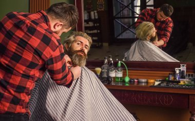 Sakallı adam. Berber dükkanı kavramı. Genç hippi sakallı adam berber dükkanında saçını kesiyor. Profesyonel kuaförlük işi. Yaşam tarzı. Usta berber saç stilini ve saç stilini kurutma makinesiyle yapıyor..