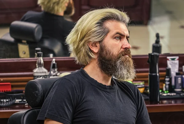 brutal bearded man at hairdresser salon with master, hair look.