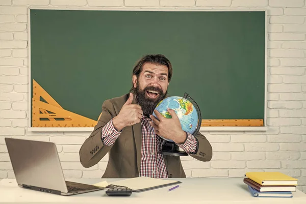 back to school. informal education. happy mature teacher hold globe and show thumb up. bearded man geographer work in classroom with map. prepare for exam. college lecturer on geography lesson.