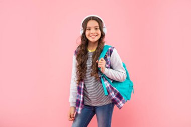 Yeni teknoloji. Çocukluk gelişimi. Modern kulaklıklı, sırt çantalı bir çocuk. Online eğitim. Okula dönüyorum. Kulaklıklı mutlu genç kız. Müzik dinle. kablosuz kulaklık aygıtı aksesuarı.