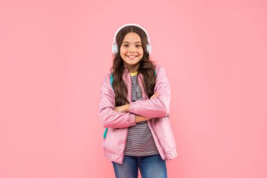 Online eğitim. Okula dönüyorum. Kulaklıklı mutlu kız. Müzik dinle. Kablosuz kulaklık cihazı aksesuarı. Yeni teknoloji. Çocukluk gelişimi. Sırt çantalı, modern kulaklıklı çocuk..