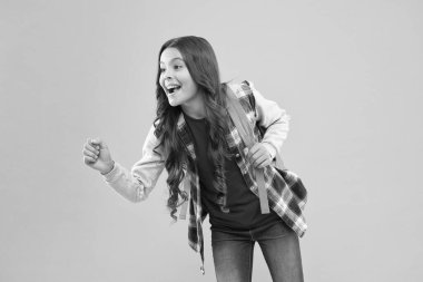 Mutlu bir okul çocuğu elinde bir şey tutuyormuş gibi davran. Sarı arka plan, reklam..