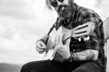 Kareli gömlekli sakallı adam şarkı söylüyor. Müzisyen müzisyen. müzik teli enstrümanı. Olgun karizmatik erkek gitarist. Sakallı ve bıyıklı adam gitar çalıyor. Sigara kötüdür..