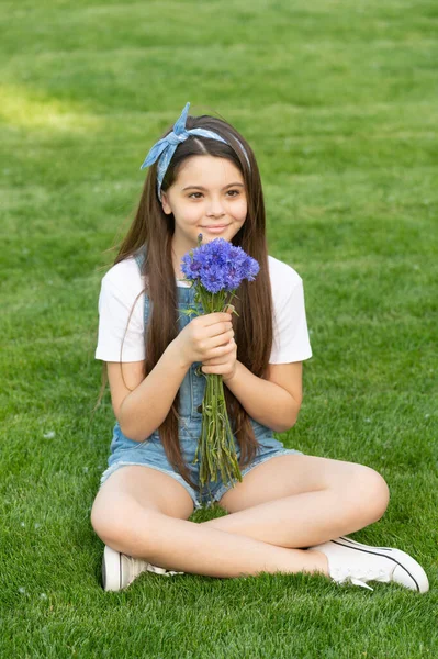 春の花と草の上に座っている陽気な女の子 — ストック写真