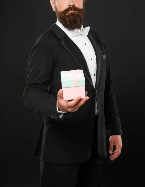 cropped man in tuxedo bow tie formalwear on black background with box. valentines day.