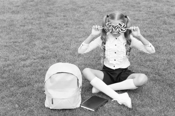 Okul Üniformalı Kız Çocuğu Yeşil Çimlerde Lolipoplarla Gözlerini Kapatırken Eğleniyor — Stok fotoğraf
