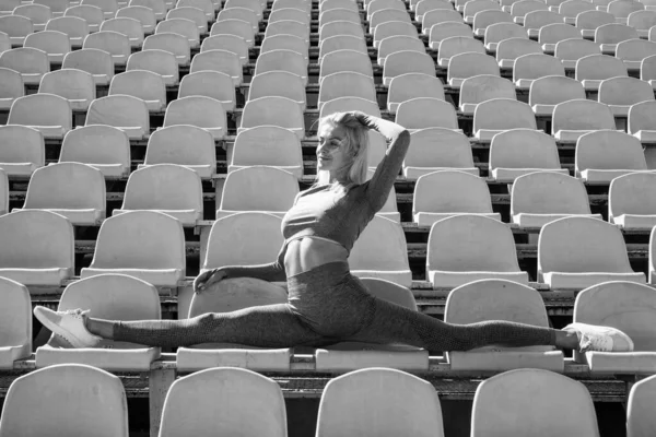 スタジアムの屋外をスプリットスポーツでストレッチする柔軟な女性 — ストック写真