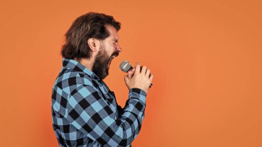 Bıyıklı ve sakallı yakışıklı hippi karaokede şarkı söylüyor..