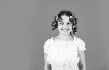 Kuaför salonu. Sevimli çocuk saçı. Kadın güzellik rutini. Moda ipuçları. Gençlik hobileri. Saç şekillendirme. Güzel kız kıvırcık saç bigudi kullanıyor. Kafasında bigudilerle gülen kızı..