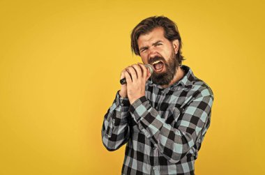 Utangaç olma. Müzik konsepti. Kareli gömlek giyen şarkı söyleyen adam. Karaoke kulübünde kendine güvenen bir erkek şarkıcı. Parti performansı. Sakallı hippi mikrofonda şarkı söylüyor.