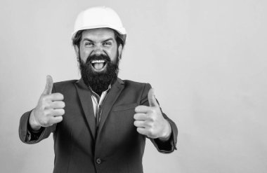 İşçi güvenliği için kasklı mühendis ya da işçi, sarı arka planda fotokopi giysisi ve iş elbisesi, başarı için başparmağınızı kaldırın..