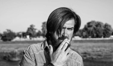 Bıyıklı vahşi sakallı hippi şık bir saç kesimi ve açık havada sigara içen sıradan bir gömlek giyiyor, rahatlıyor..