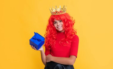 Sarı arka planda mevcut kutusuyla taç giymiş mutlu çocuk..