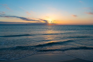 Yaz plajında deniz suyuyla huzurlu bir gün batımı..
