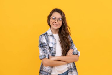 Sarı arka planda damalı gömlek ve gözlüklü mutlu genç çocuk..