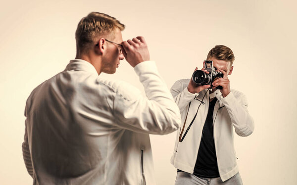 confident model photographer. twins brother in white. photographing. beauty and fashion. similar appearance. male friendship. men friends. two cousin with retro photo camera. young confident brothers.