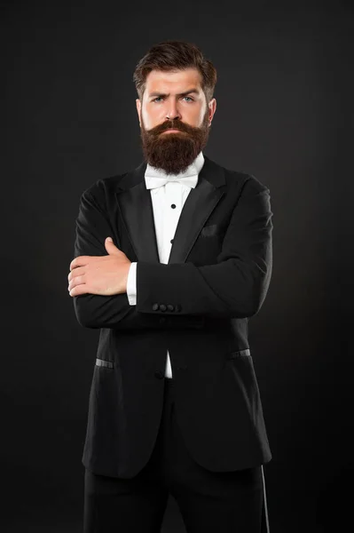 bearded businessman in tuxedo on black background, bow tie.