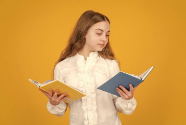 Beyaz gömlekli ciddi bir çocuk ders çalışmaya hazır. Ödev kitabı okuyor. Sarı arka plan, edebiyat..