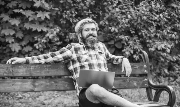 Work and relax. Working online. Hipster inspired work in park. Modern laptop. Remote job. Fresh air. Mobile internet. Online shopping. Agile business. Bearded guy sit bench park nature background.