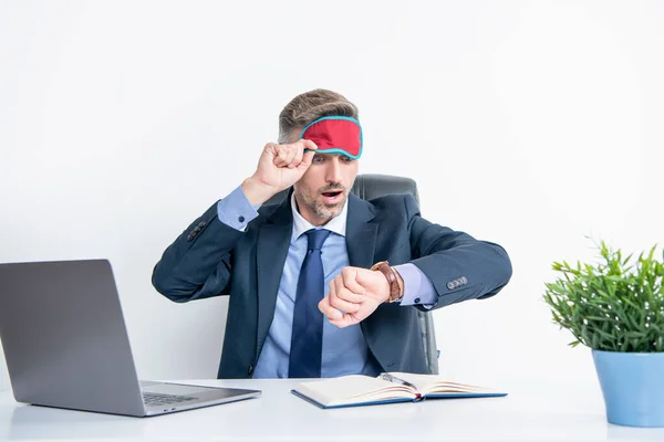 tired businessman check time in sleep mask at workplace.