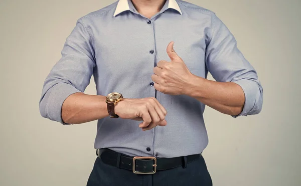 cropped punctual man in shirt check time on hand watch and show thumb up, punctuality.