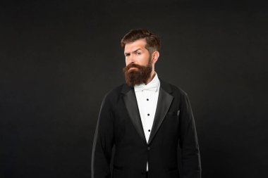 Smokinli papyonlu ciddi sakallı adam. Siyah arka planda resmi giyimli uşak. erkek resmi moda.