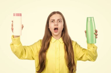 Şaşırmış genç kız şampuan ya da saç kremi şişesini sunuyor beyaza izole edilmiş, karar.