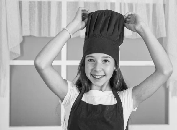 幸せな子供は料理の制服を着る 帽子とエプロンのシェフの女の子 キッチンで料理を作ってる キャリアを選択する 台所の手伝いだ 料理も料理も 幸せな子供時代 — ストック写真