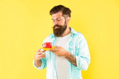 Sakallı adam sabah kahvesini sarı arka planda içer, kahve fincanı....