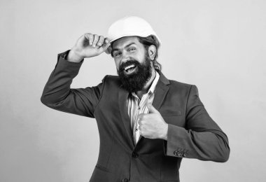 Sakallı, mutlu ve başarılı bir adam. Mühendislik kavramı. Mimari ve bina. Erkek müteahhit koruma için resmi takım elbise ve kask giyiyor. İnşaat projesinde çalışıyorum. başparmak yukarı.