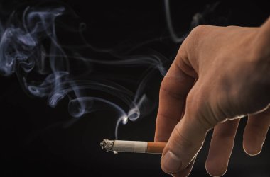 Erkek eli dumanlı sigara dumanı arka planda, sigara içiyor..