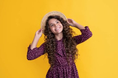 Sarı arka planda uzun kıvırcık saçlı, hasır şapkalı çocuk gülüşü..