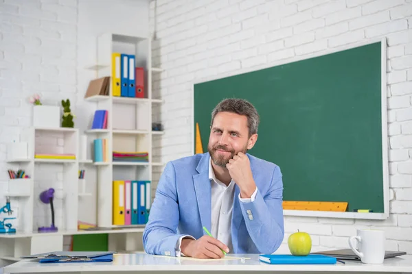 happy school tutor in classroom at blackboard.