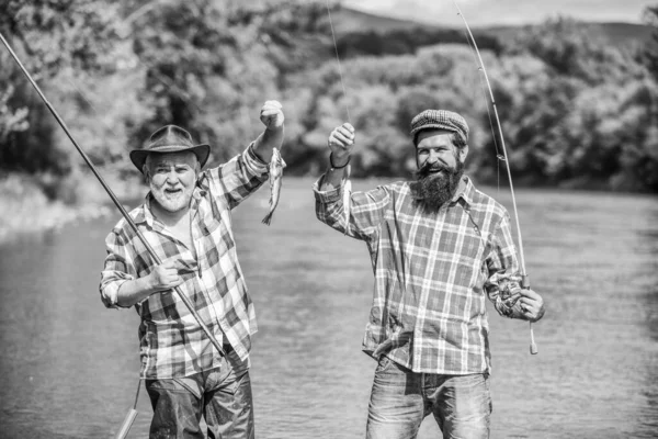 Mature man with friend fishing. Summer vacation. Happy cheerful people. Fishing freshwater lake pond river. Bearded men catching fish. Family time. Fisherman with fishing rod. Activity and hobby.