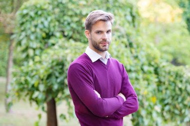 Havalı giyinen yakışıklı genç adam dışarıda ellerini çapraz yaptı..