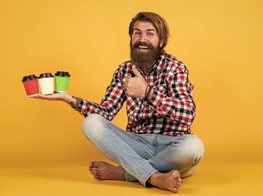 En iyi gün başlıyor. Teslimat. İlham almak için kahve lazım. Mutlu sakallı adam sabah kahvesini içiyor. Adam kağıt bardaktan sıcak çay içiyor. Günaydın. Enerjik sıcak içecek..