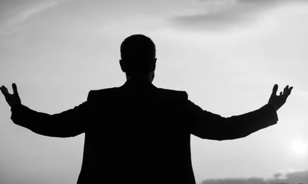 personal achievement goal. man silhouette on sky background. confident businessman with raised hands. daily motivation. enjoying life and nature. business success. freedom.