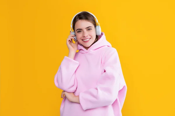 happy young woman listen music in headphones on yellow background.