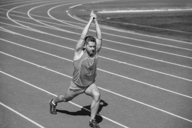 Erkek koşucu sporcu antrenman yapıyor ve dışarıda egzersiz yapıyor, esniyor..