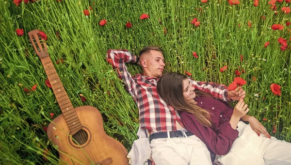 Cute couple. happy family. country music. spring nature beauty. love and romance. romantic relationship. couple in love with guitar. man and woman in poppy flower field. summer vacation.