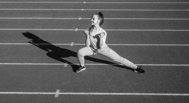 Stadyum koşu pistinde dambıl çalıştıran sağlıklı bir kız çocuğu..