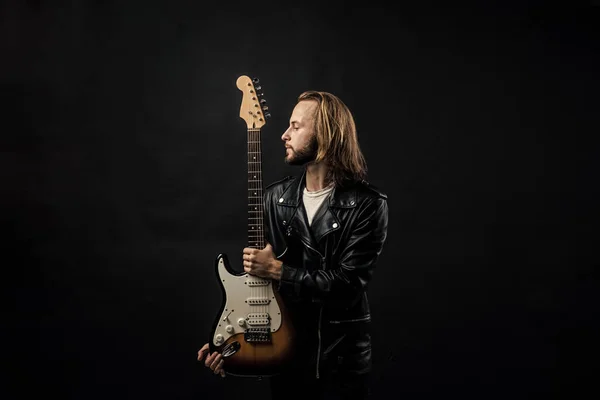 rock music style star. musician guitar player. masterfully playing rock music. stylish crazy man. string musical instrument. bearded rocker in leather jacket. man long hair play electric guitar.