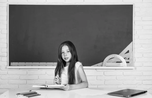 学校に戻って 10代の女の子が黒板近くの教室で働いています 陽気な子供の学習科目 近代教育です 知識の日だ 子供の生徒はテーブルに座る 女の子は大学生で — ストック写真