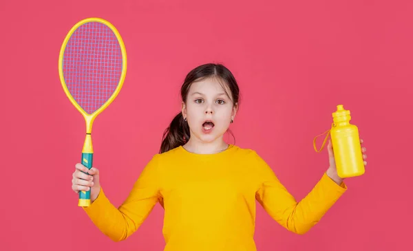 Изумленный Ребенок Держит Теннисную Ракетку Бутылку Воды Розовом Фоне — стоковое фото