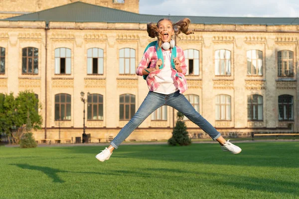 Happy energetic teen girl jumping in school yard outdoors, Knowledge day.