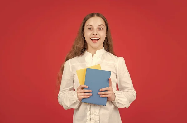 白いシャツを着た驚くべき子供は赤い背景の本で宿題を勉強する準備ができて学校に戻る — ストック写真
