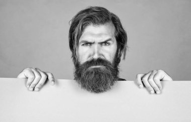 serious bearded brutal man with moustache hold paper shit for copy space, wanted.