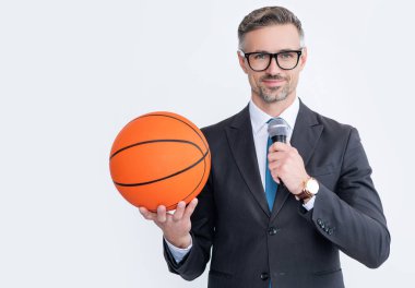 happy mature man in suit hold basketball ball and microphone isolated on white background.